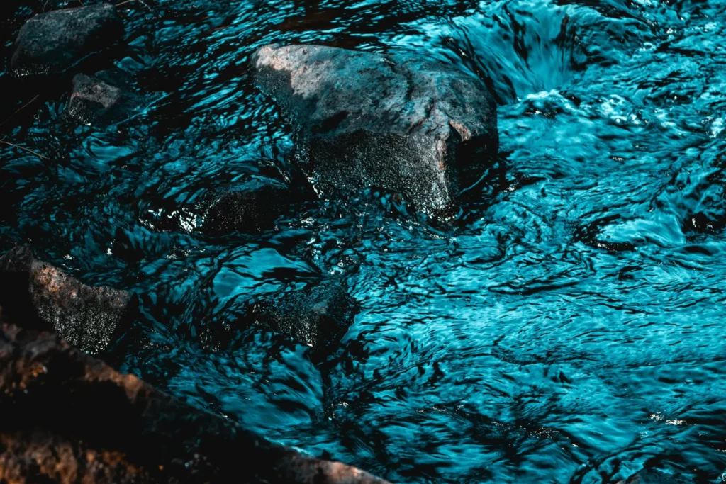 Ruisseau d'eau vive bleu turquoise s'écoulant sur des rochers.